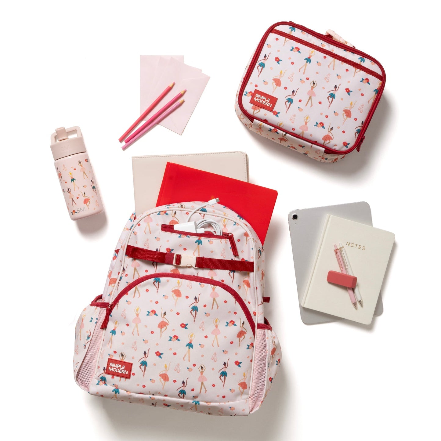 Flat lay of 18L Fletcher collection items arranged on blush pink and cream background, featuring burgundy red accents with peachy coral, navy blue, and teal coordinating pieces.
