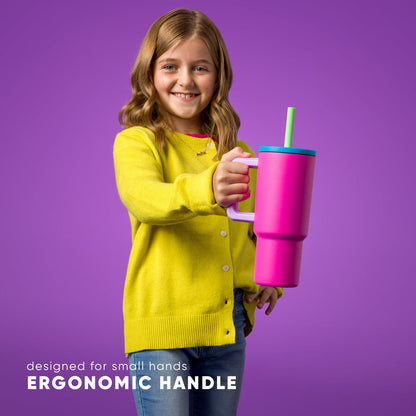 Girl in yellow sweater holding bright pink Simple Modern 24oz Kids Trek tumbler with turquoise lid, green straw, and light pink ergonomic handle designed for small hands against purple background.