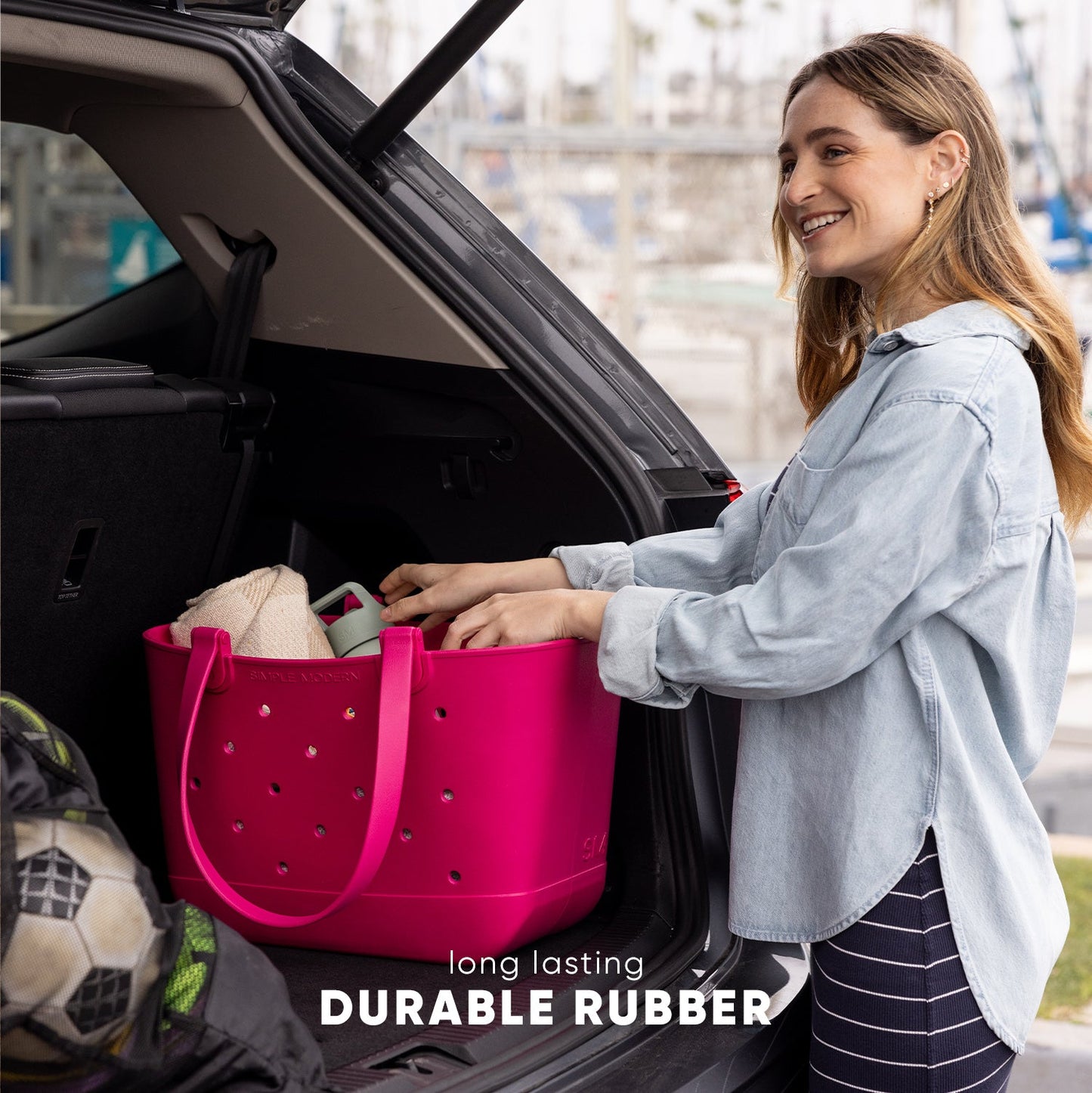 Vibrant hot pink durable rubber getaway tote bag displayed against a cool-toned background, highlighting its bold color and sturdy construction for travel.
