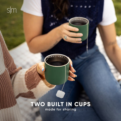 Two people holding forest green insulated cups, wearing white and cream clothing with navy blue accents.