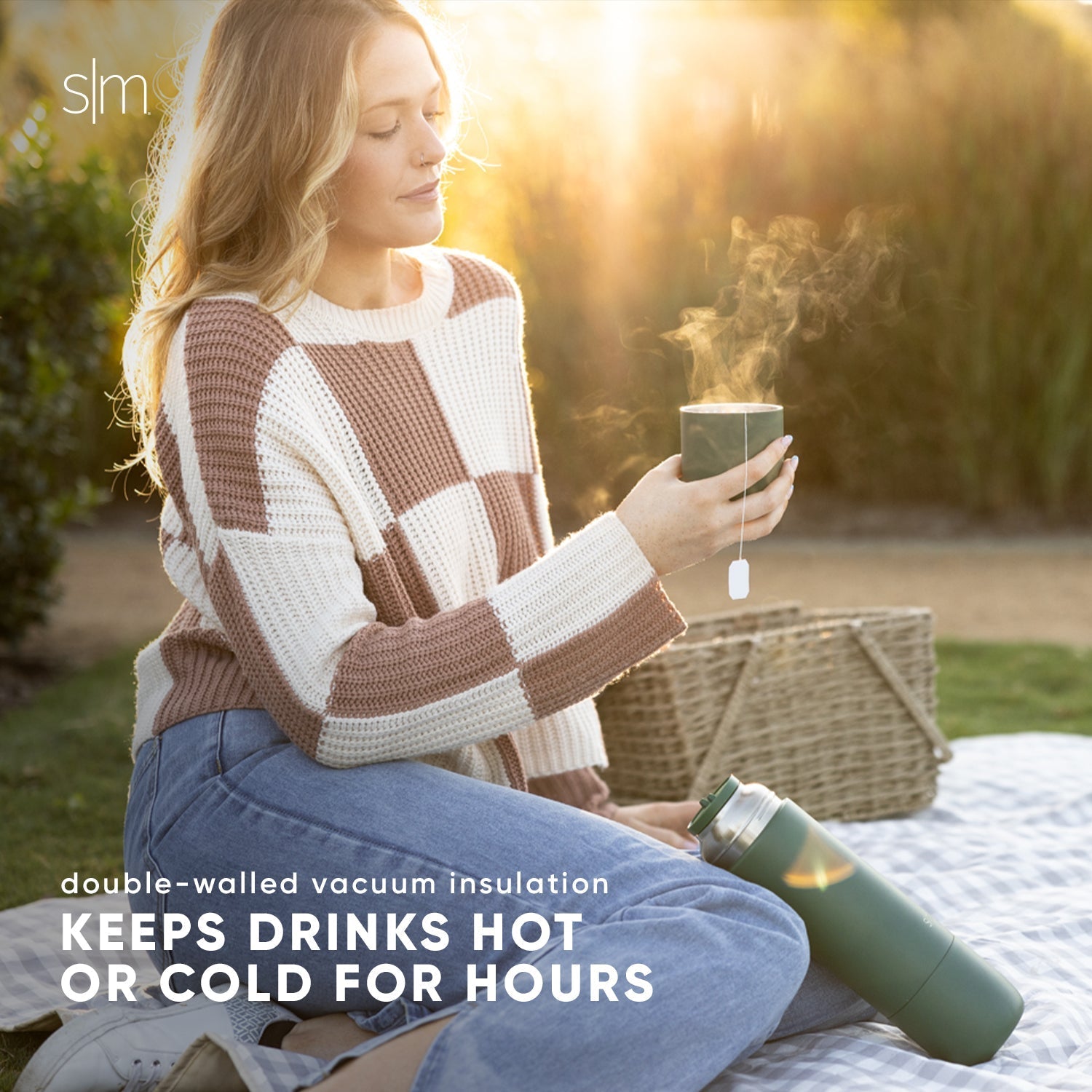 Woman wearing a color-blocked sweater in cream and taupe tones, bathed in warm golden sunlight highlighting earth tones and sage colors in the scene.